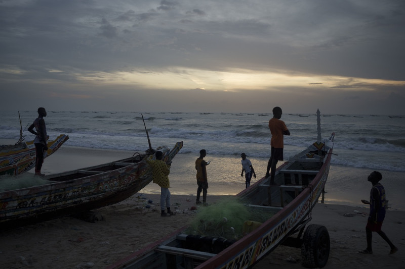 Jóvenes senegaleses se reúnen alrededor de piraguas en la playa al atardecer en Fass Boye, Senegal, 29 de agosto de 2023.