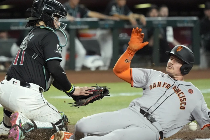 Matt Chapman, de los Gigantes, se barre para llegar a salvo en el plato para anotar con un jonrón de campo, ante el intento de retirarlo de José Herrera, de los Damondbacks, durante la tercera entrada del juego.