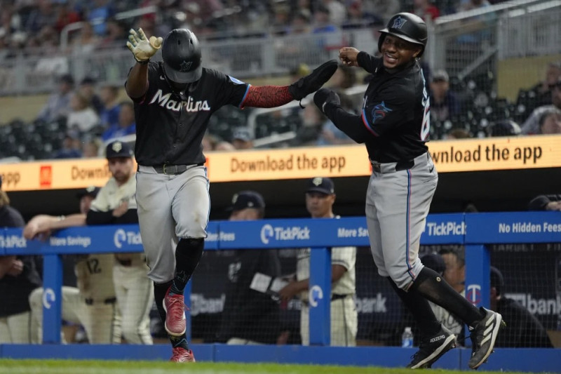 El dominicano Otto López (izquierda) y Xavier Edwards, de los Marlins de Miami, festejan tras anotar en la 13ra entrada del juego ante los Mellizos de Minnesota.