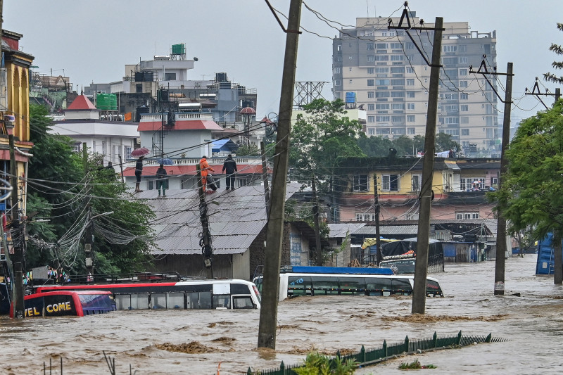 Los residentes suben a un tejado mientras su vecindario se sumergía en las aguas de la inundación después de que el río Bagmati se desbordara tras las fuertes lluvias monzónicas en Katmandú el 28 de septiembre de 2024. Las inundaciones y deslizamientos de tierra causados ​​por los fuertes aguaceros en Nepal mataron al menos a 10 personas en todo el país del Himalaya, y los equipos de rescate equipos que buscan a 18 desaparecidos, dijo un responsable de desastres el 28 de septiembre.