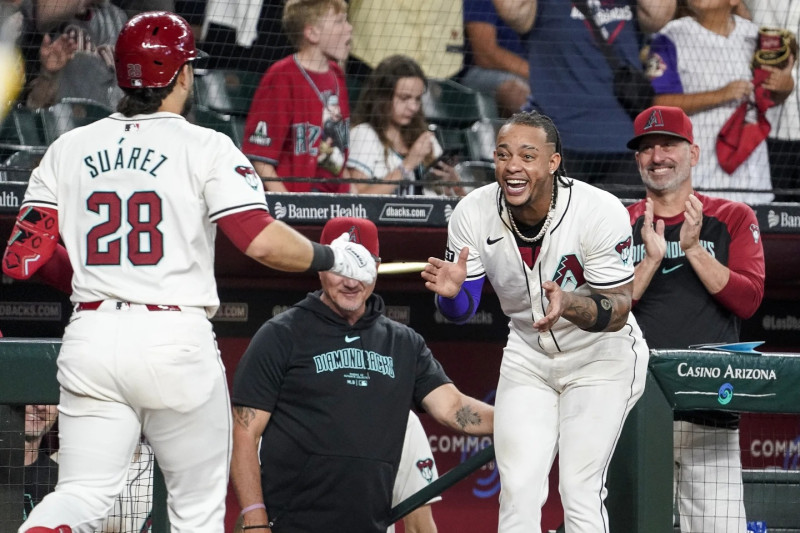 etel Marte, de los Diamondbacks de Arizona, a la derecha, y el manager Torey Lovullo, a la extrema derecha, saludan a Eugenio Suárez después del jonrón de Suárez contra los Padres de San Diego durante la séptima entrada.