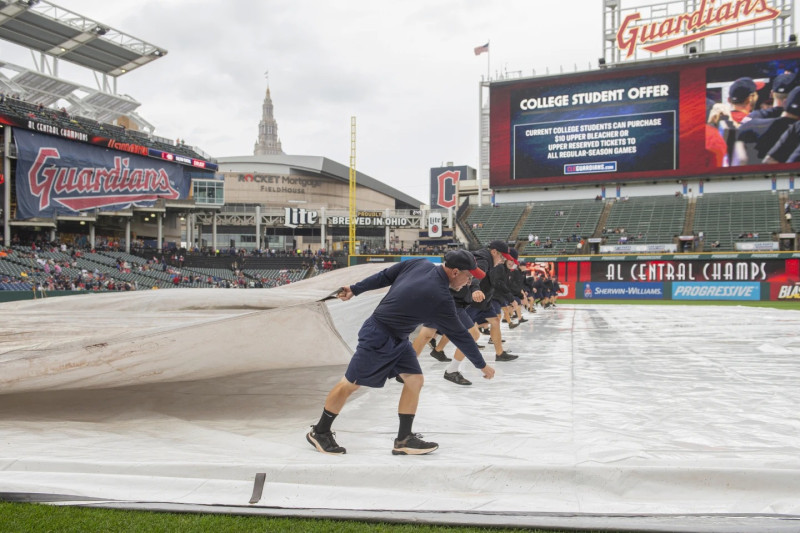 El equipo de mantenimiento de Cleveland coloca la lona del cuadro interior antes del partido entre los Guardians y los Astros en Cleveland,