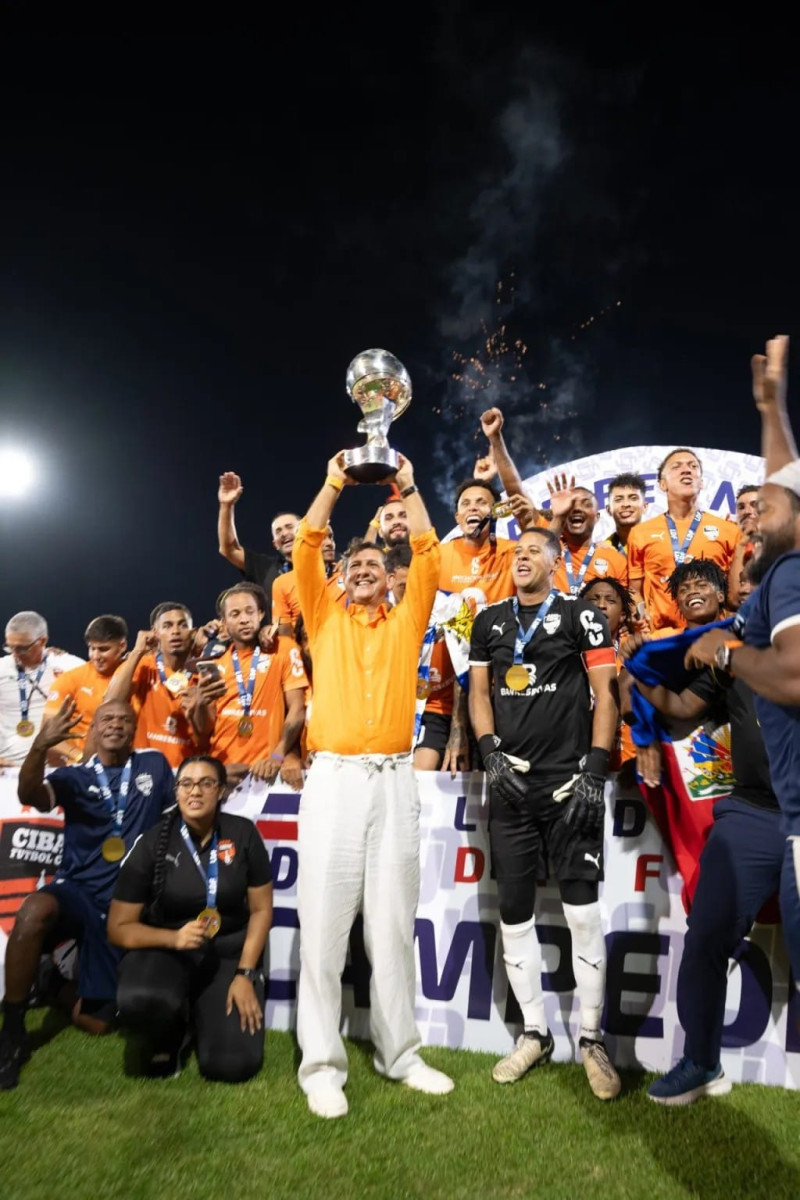 El presidente de Cibao FC, Manuel Estrella, levanta la copa de campeones  junto a los integrantes del equipo, el sábado en Santiago.