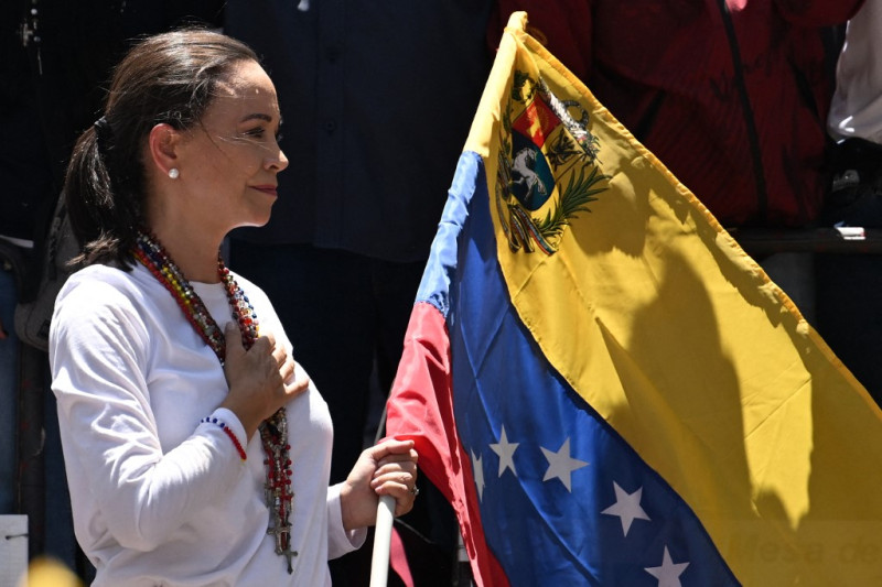 La líder de la oposición venezolana, María Corina Machado, sostiene una bandera nacional venezolana mientras hace un gesto desde lo alto de un camión durante una manifestación para protestar por los resultados de las elecciones presidenciales, en Caracas, el 3 de agosto de 2024.