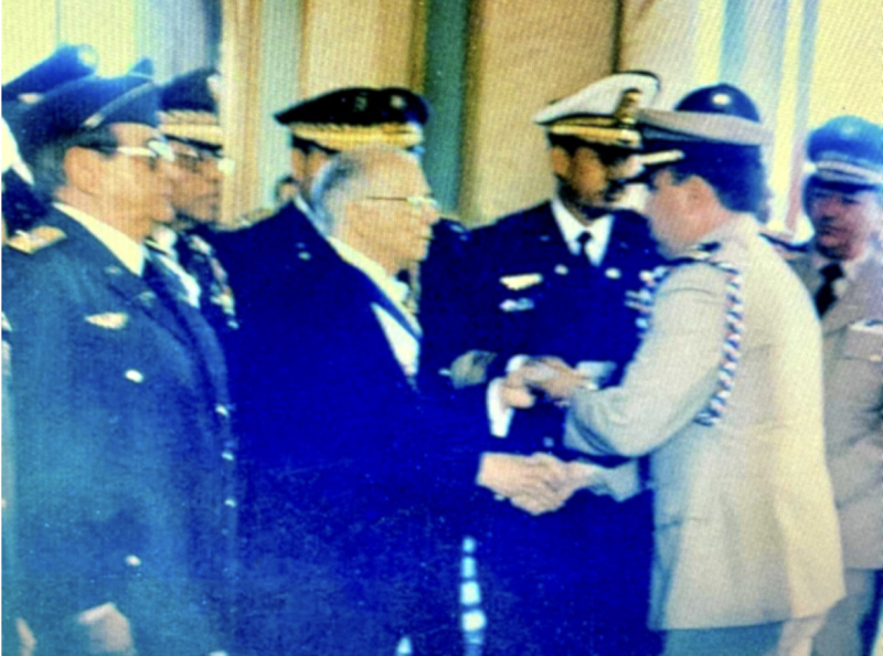 Homero Luis Lajara Solá recibiendo del presidente Joaquín Balaguer las insignias de teniente de navío (capitán). A la derecha del presidente, teniente general Elías Wessin y Wessin, secretario de Estado de las Fuerzas Armadas; detrás, el mayor general Luis M. Pérez Bello; a la izquierda, el vicealmirante José Santos Sánchez y el mayor general Constantino Matos Villanueva, jefes de Estado Mayor de la Marina de Guerra y del Ejército Nacional, respectivamente. Palacio Nacional, (1991).