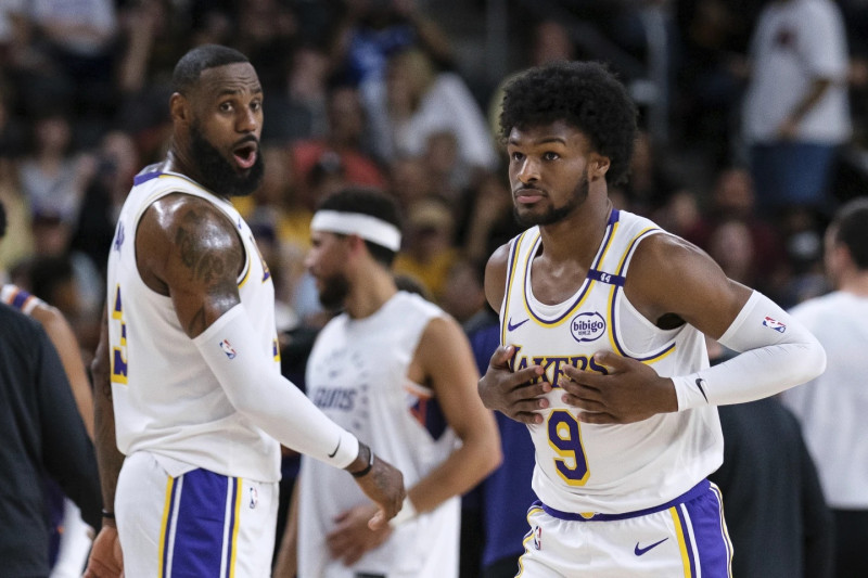 Bronny James (9), a la derecha, entra a la cancha con el alero de Los Angeles Lakers, LeBron James (23), durante la primera mitad de un partido.