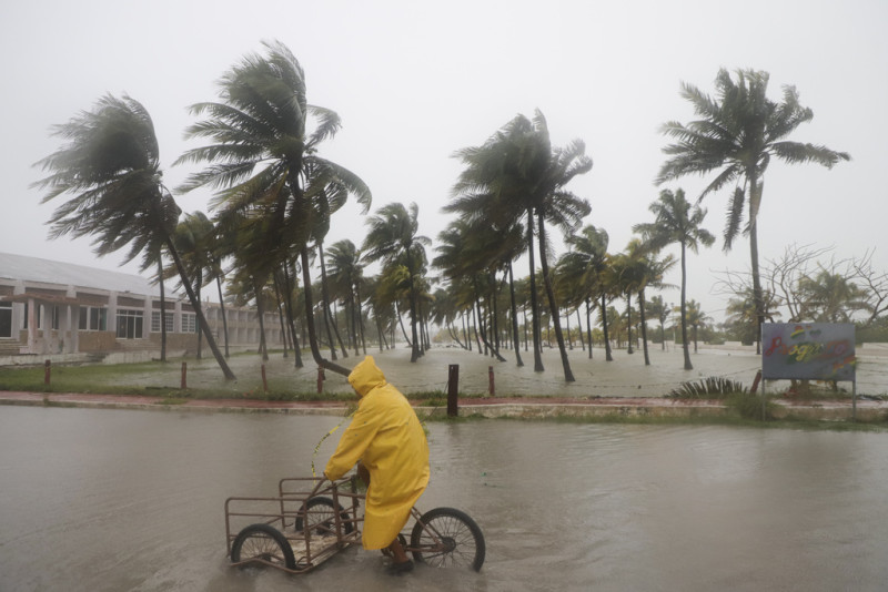 Una persona monta su bicicleta a través de una calle inundada mientras el huracán Milton pasa frente a la costa de Progreso, en el estado de Yucatán, México, el martes 8 de octubre de 2024