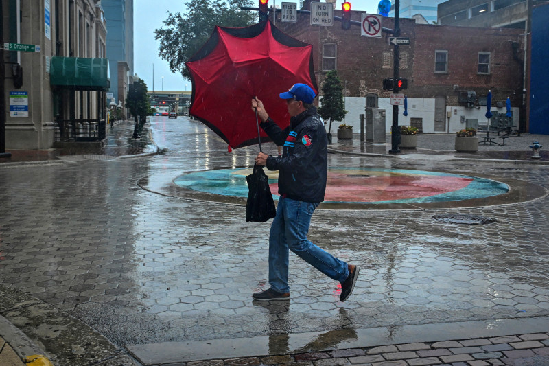 A man holds his umbrella in downtown Orlando, Florida, on October 9, 2024, as Hurricane Milton approaches. - Florida residents fled or just hunkered down in the final hours October 9, 2024 before Milton pummels the state, as government emergency relief efforts were dragged to the center of the US election. (Photo by GIORGIO VIERA / AFP)