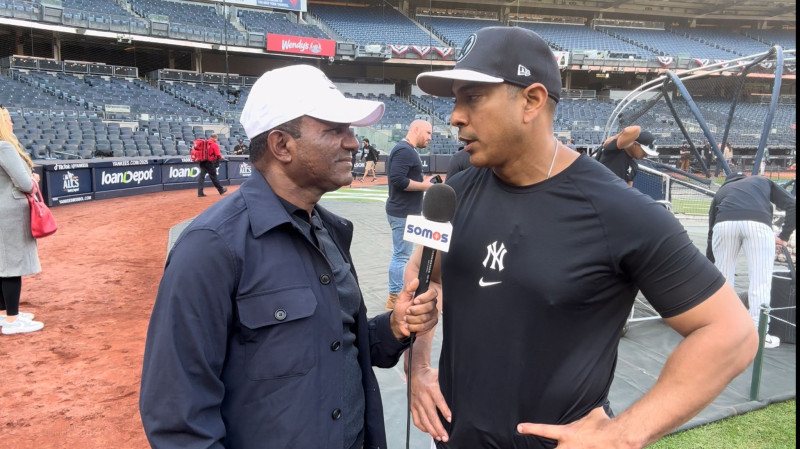 Daniel Reyes conversa con el coach de tercera de los Yankees, Luis Rojas.