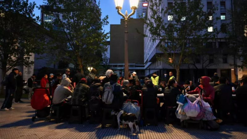 Unas personas comen alimentos distribuidos por la organización Red Solidaria el 25 de septiembre de 2024 en la Plaza de Mayo de Buenos Aires.