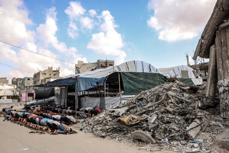 Muslim worshippers perform the weekly Friday prayers in a tent enclosure by destroyed buildings in Khan Yunis in the southern Gaza Strip on October 18, 2024 amid the ongoing war in the Palestinian territory between Israel and Hamas. (Photo by BASHAR TALEB / AFP)