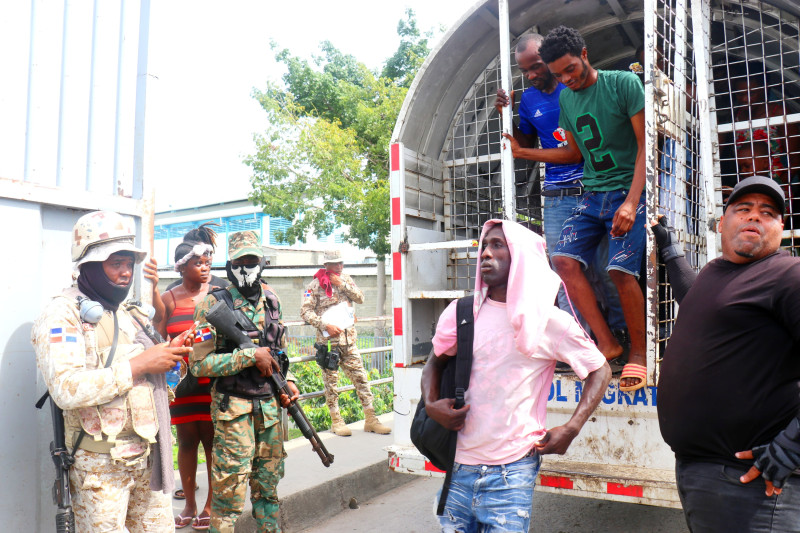 Ilegales haitianos capturados bajan de una unidad de Migración, listos para emprender el camino de vuelta a su país.