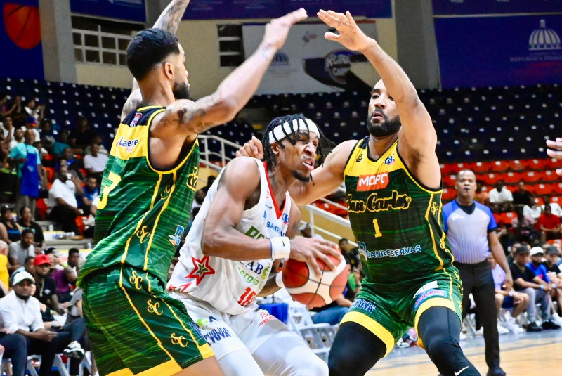 Jassel Pérez, de Bameso, trata de escapar de la doble defensa de Juan Guerrero y Anyeuri Castillo, de San Carlos, en el segundo partido de la semifinal del TBS Distrito.