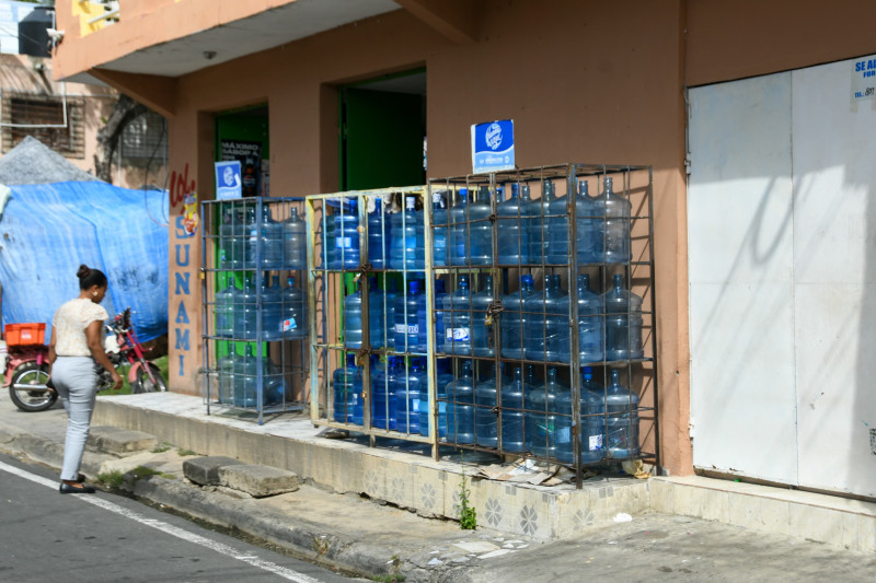 Botellones de agua para consumo humano expuesta a la venta al descubierto en un anaquel de colmado en Santo Domingo Este.