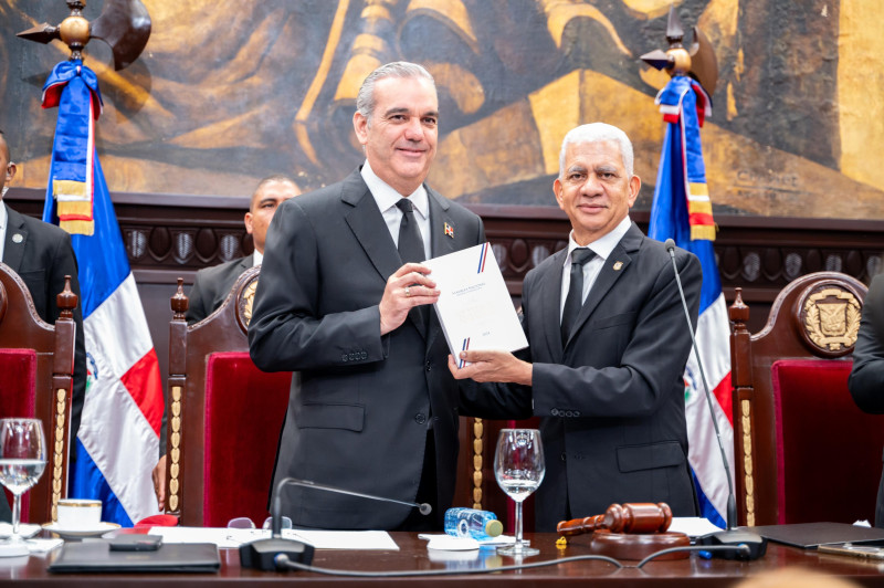 El presidente Luis Abinader recibe del presidente del Senado Ricardo de los Santos un ejemplar de la nueva Constitución de la República.