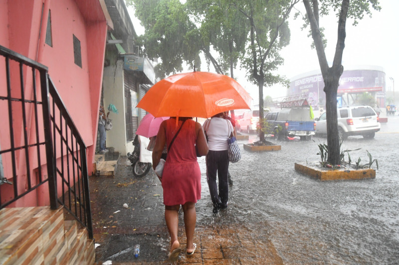 Varias personas se desplazan por una acera inundada del Distrito Nacional