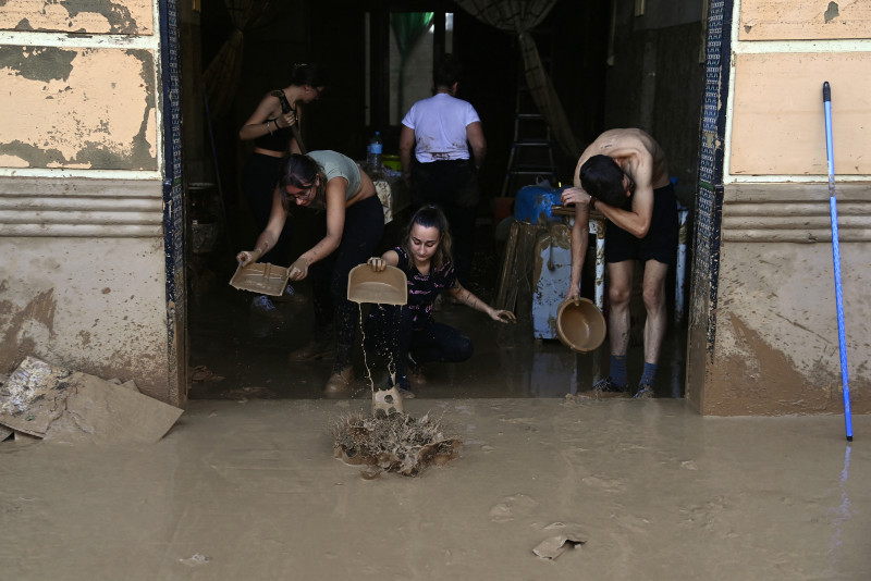 La gente intenta limpiar una casa mientras la calle está cubierta de barro el 31 de octubre de 2024 después de que las inundaciones repentinas afectaran a La Torre, en Valencia, este de España.