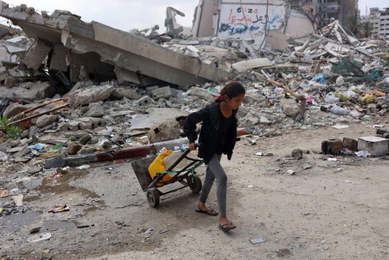 Una niña palestina transporta agua mientras pasa junto a un edificio derrumbado en la ciudad de Gaza el 2 de noviembre de 2024, en medio de la guerra entre Israel y Hamás