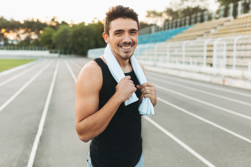 Joven sonriente en una pista de atletismo. Foto de Arthur Hidden-Freepik .