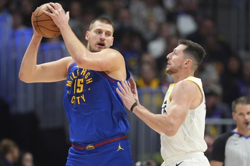 Nikola Jokic, de los Nuggets de Denver, busca enviar un pase frente a Drew Eubanks, del Jazz de Utah.