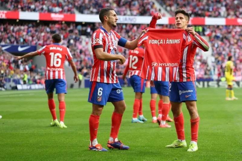 l atacante argentino Giuliano Simeone (derecha) celebra su gol contra Las Palmas con una camiseta en homenaje a las víctimas de las inundaciones de Valencia.