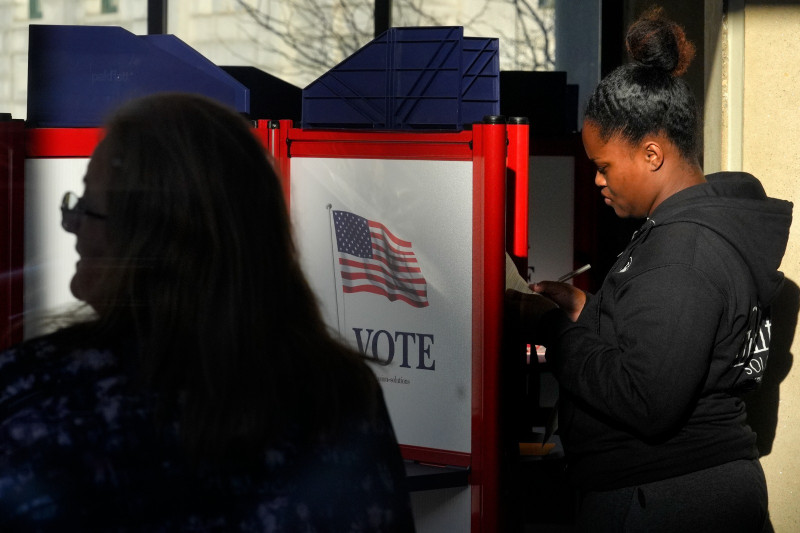 Un votante, a la derecha, llena su boleta durante la votación anticipada en las elecciones generales, el viernes 1 de noviembre de 2024, en Fall River, Massachusetts.