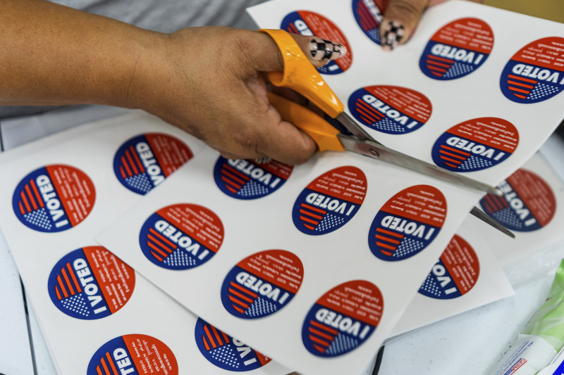 Un voluntario ayuda a cortar las calcomanías con la leyenda "Yo voté"