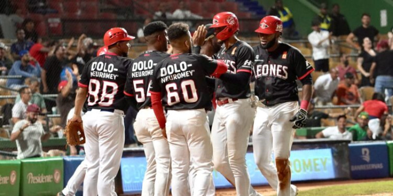 Jugadores de los Leones celebran luego de llegar al plato.