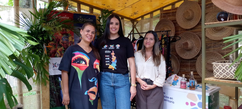 Una joven representante de RAP Pacífico, Stephanía Sanclemente y Andrea Ortiz reciben a los visitantes en la caseta de la organización que promueve el desarrollo social y económico de los departamentos El Choco, Valle del Cauca, Cauca y Nariño.