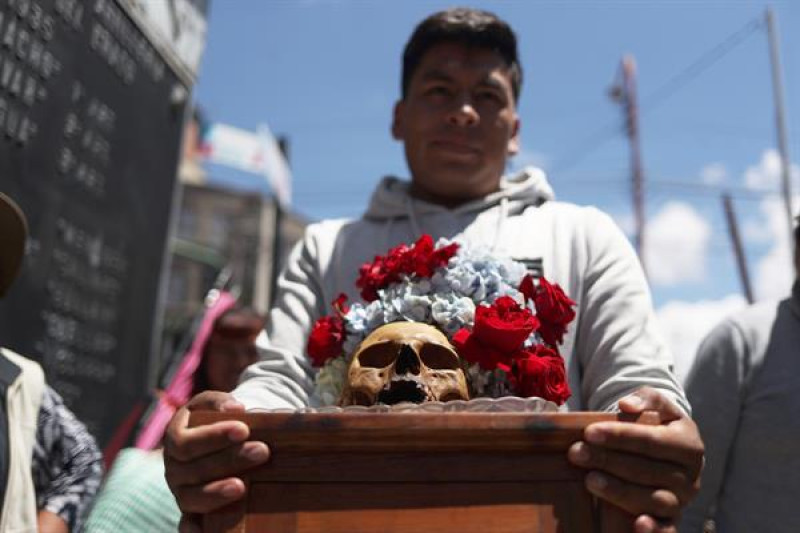 Un hombre carga un cráneo humano o "ñatita" en el cementerio general durante la celebración de las "ñatitas" este viernes en La Paz (Bolivia). La devoción a las "ñatitas" o cráneos humanos arraigada en varias familias bolivianas pasa poco a poco a generaciones más jóvenes que se convierten en los nuevos protectores de esta práctica que, según dicen, tienen como retribución milagros y bendiciones de las almas que ocuparon esos restos humanos.