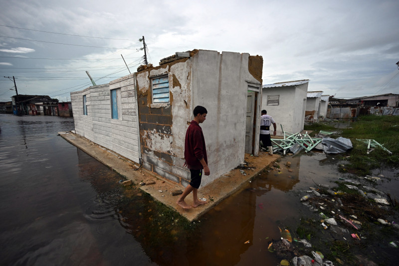 Un joven camina afuera de una casa dañada y rodeado de agua de lluvia después del paso del huracán Rafel en Batabano, provincia de Mayabeque, Cuba, el 7 de noviembre de 2024.