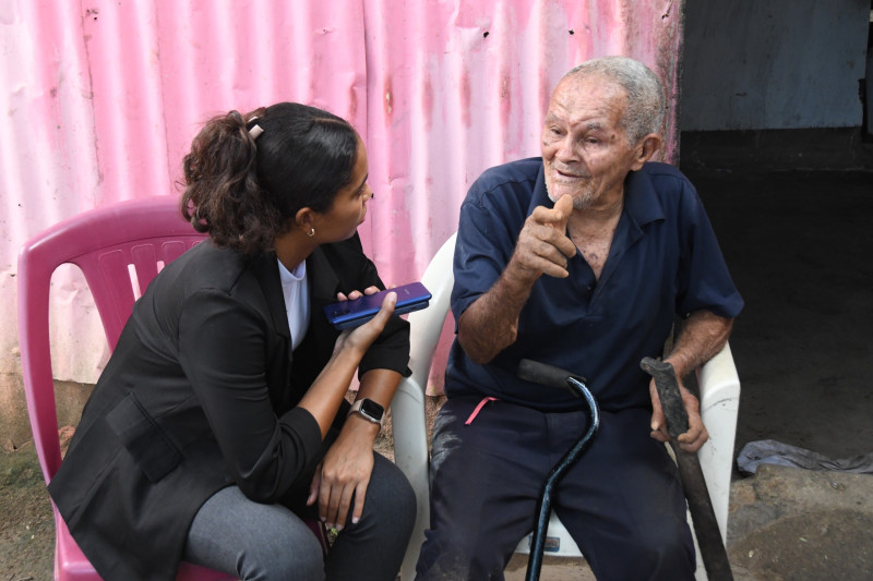 La periodista Melanie Cuevas durante la entrevista con el adulto mayor residente en La Caleta.