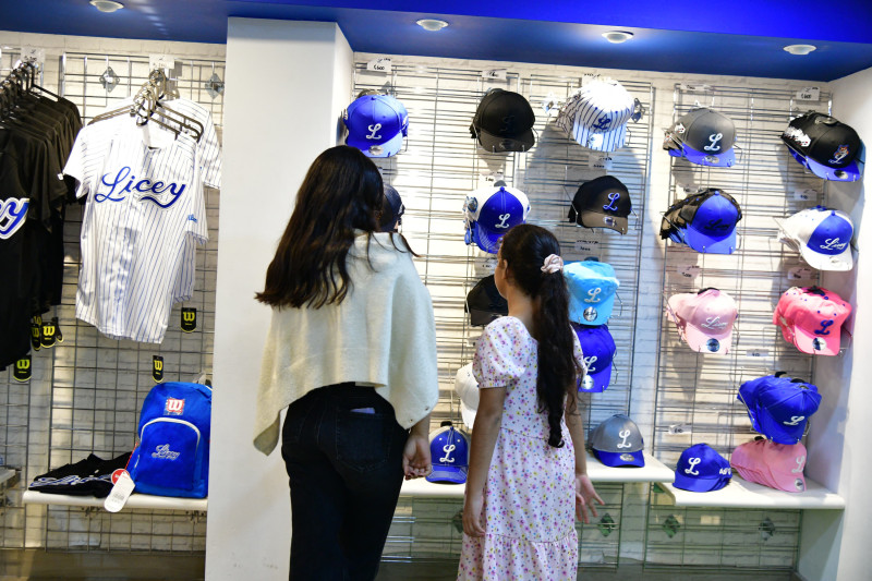 Momento en el que una mujer y su hija observan los artículos de la tienda oficial de los Tigres del Licey.