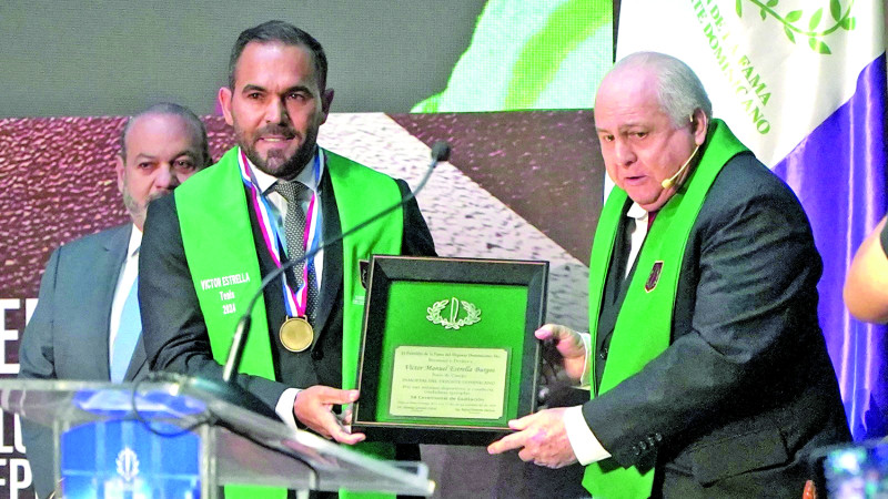 Víctor Estrella muestra placa de reconocimiento de manos del presidente de honor Luis Esmurdoc.