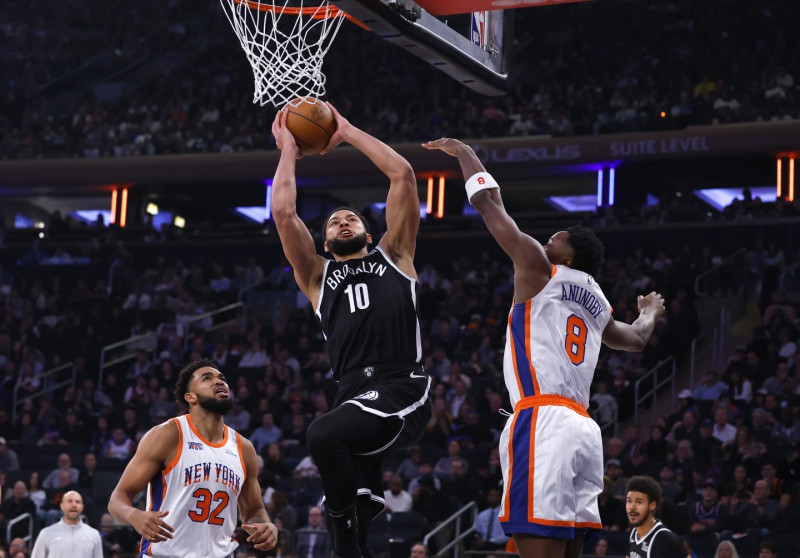 Ben Simmons, de los Nets, trata de encestar frente a la defensa de OG Anuboby, de los Knicks, mientras Karl-Anthony Towns observa en el partido del baloncesto de la NBA.