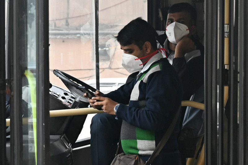 Un conductor de autobús y un revisor llevan mascarillas en medio de la contaminació