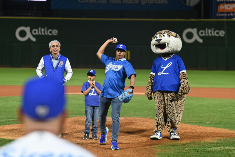 Félix Sánchez, acompañado de su hijo, realiza el lanzamiento de honor del juego contra el Escogido. Observa Ricardo Ravelo, presidente del Licey.