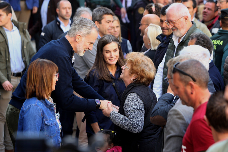 El rey Felipe VI de España habla con una mujer junto a la reina Letizia, ayer en Chiva.