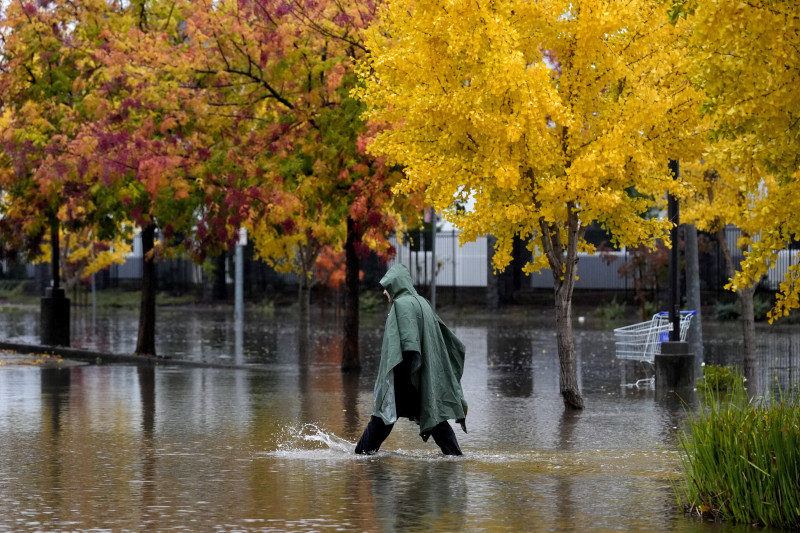 Un peatón camina por una calle inundada durante una tormenta