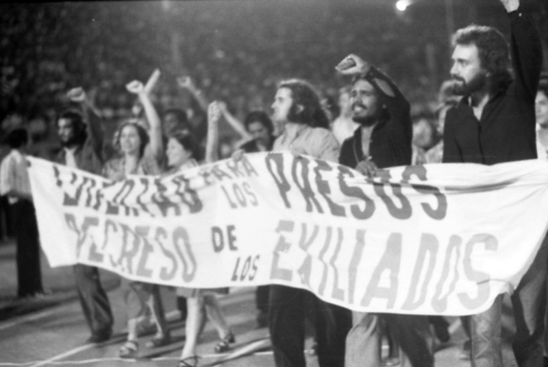 Esta foto fue primera plana de los periódicos del 1974. Artistas y viudas de dominicanos asesinados desfilaron por el Estadio Olímpico con este cartelón que decía: "Libertad para los presos políticos y regreso de los exiliados"