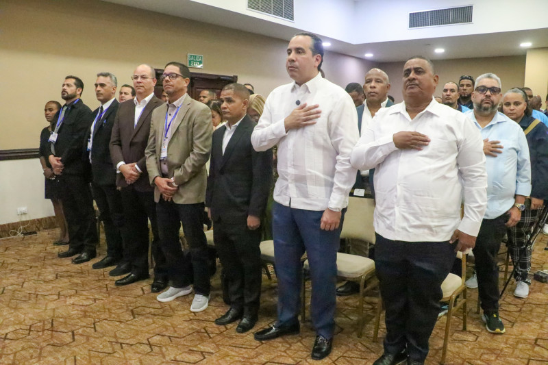 El director del Inefi, Alberto Rodríguez Mella, junto a varios de los ejecutivos y participantes, escucha las notas del Himno Nacional.