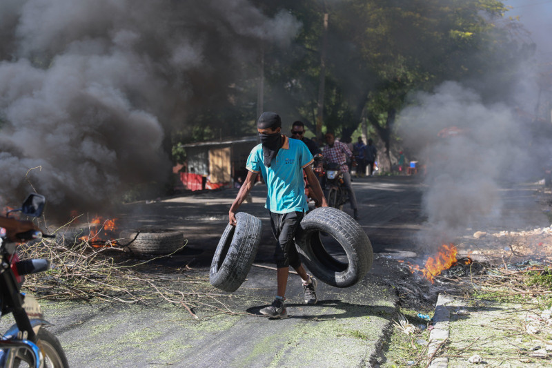 Un residente lleva neumáticos para colocarlos en una barricada en llamas para disuadir a los pandilleros de entrar a su vecindario, en Puerto Príncipe, el 19 de noviembre de 2024.