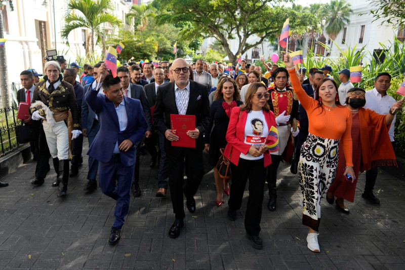 El presidente de la Asamblea Nacional, Jorge Rodríguez (en el centro), sostiene un proyecto de ley aprobado por los legisladores que codifica las sanciones económicas como un crimen contra la humanidad.