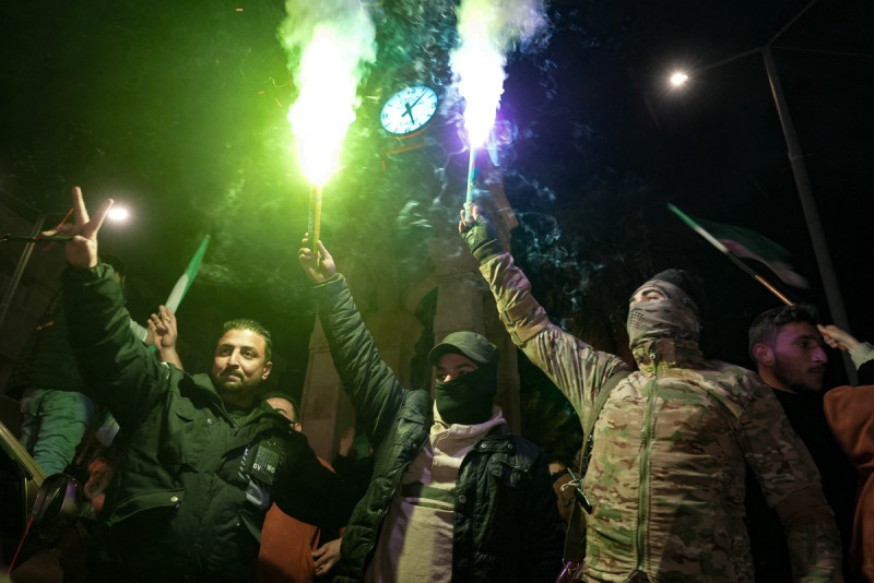 Residentes de la ciudad siria de Idlib encienden bengalas mientras celebran el control de varios distritos de Alepo por los yihadistas