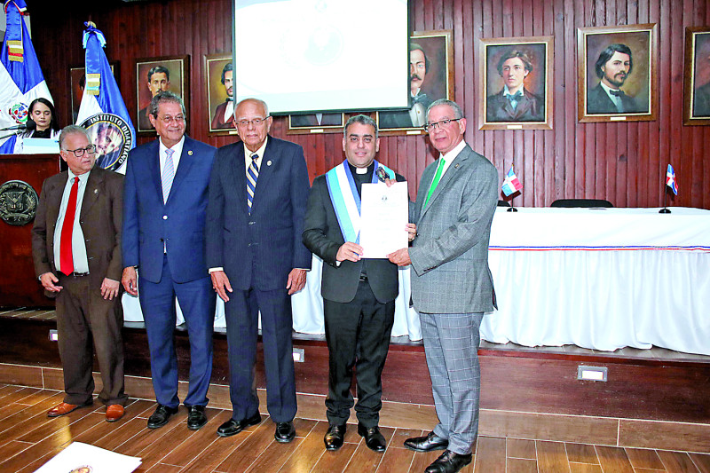 El padre Isaac García recibe su pergamino de Wilson Ramírez.