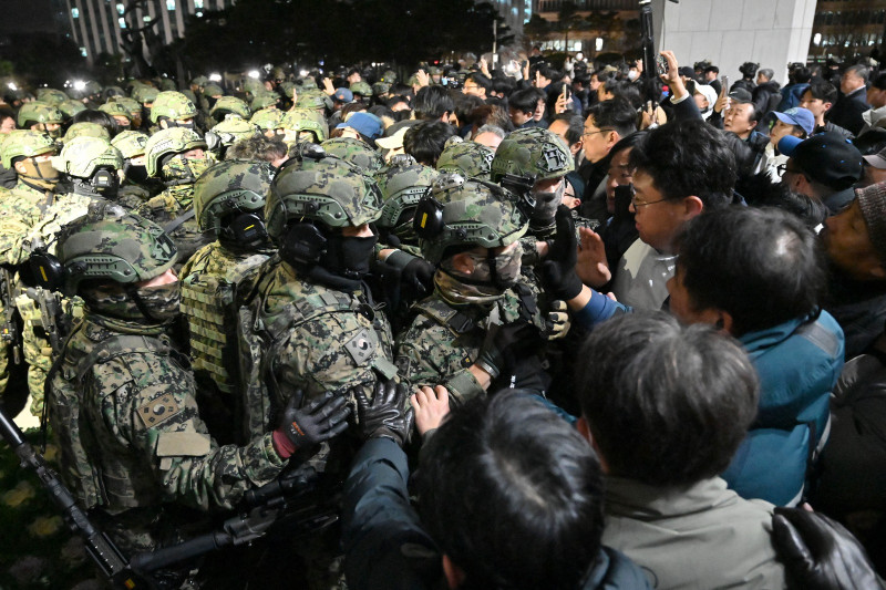 Soldados intentan entrar en el edificio de la Asamblea Nacional en Seúl el 4 de diciembre de 2024, después de que el presidente de Corea del Sur, Yoon Suk Yeol, declarara la ley marcial. - El presidente de Corea del Sur, Yoon Suk Yeol, declaró el 3 de diciembre la ley marcial, acusando a la oposición de ser "fuerzas antiestatales" y diciendo que estaba actuando para proteger al país de las "amenazas" planteadas por el Norte. (Foto de Jung Yeon-je / AFP)