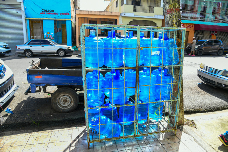 Mientras en Santo Domingo estos envases con agua siguen expuestos al sol, embotelladores de Santiago afirman que se ha avanzado, aunque aun están lejos del 100%.