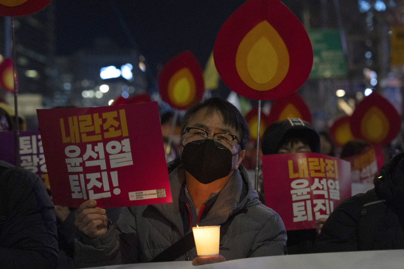 Un manifestante sostiene un cartel con la leyenda "Renuncia, Yoon Suk Yeol" mientras se une a otros en una marcha hacia la oficina presidencial después de una vigilia con velas contra el presidente surcoreano Yoon Suk Yeol, en Seúl, Corea del Sur, el miércoles 4 de diciembre de 2024 (Foto AP/Ng Han Guan)