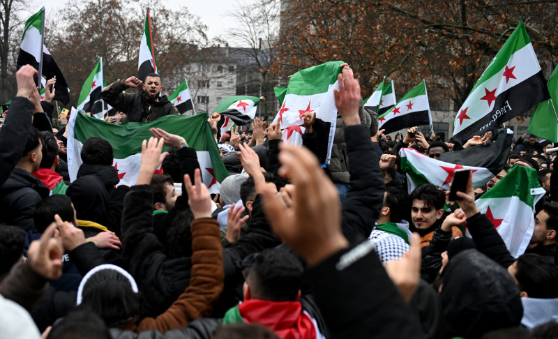 Miembros de la comunidad siria ondean banderas sirias mientras asisten a una manifestación el 8 de diciembre de 2024 en Berlín, Alemania, para celebrar el fin del gobierno del dictador sirio Bashar al-Assad después de que los combatientes rebeldes tomaran el control de la capital siria, Damasco, durante la noche.