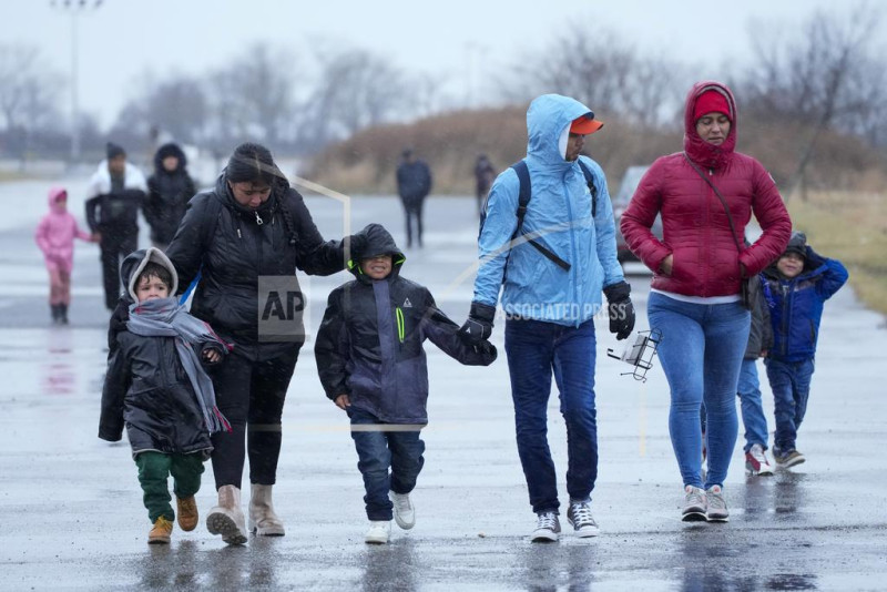 Inmigrantes corren bajo la lluvia hacia las tiendas de campaña en el recinto Floyd Bennett Field, el martes 9 de enero de 2024, en Nueva York.